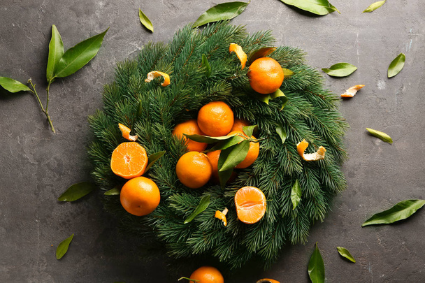 Fir tree branches with tasty juicy tangerines on grey background - 写真・画像