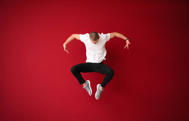 Genç erkek dansçı renk arka plan üzerinde atlama - Fotoğraf, Görsel