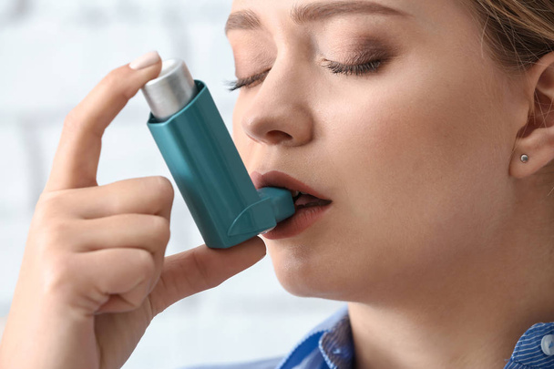 Young woman with inhaler having asthma attack, closeup - Fotó, kép