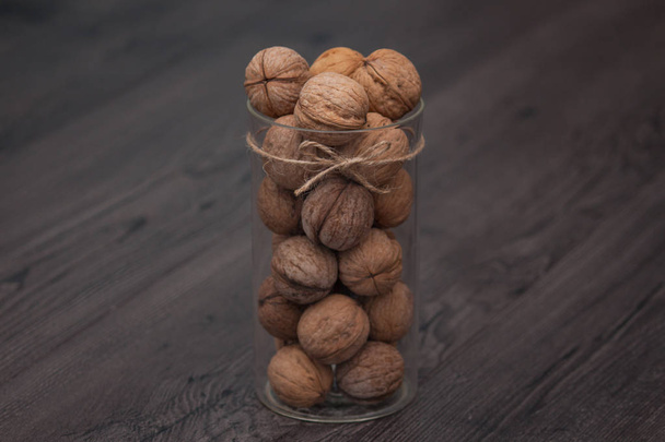 Whole walnuts in a glass jar on a rustic wooden background. Healthy food, snack. - Valokuva, kuva