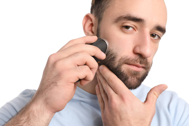 Pohledný muž používající elektrický holící strojek proti bílým pozadím - Fotografie, Obrázek