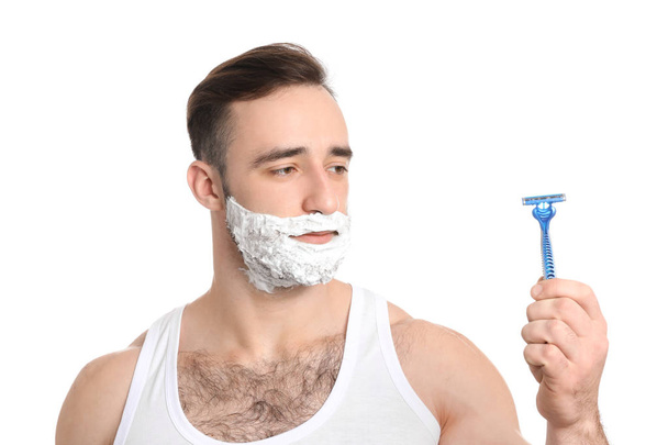 Komea mies, jolla on partavaahto kasvoillaan ja partaveitsi valkoisella taustalla
 - Valokuva, kuva