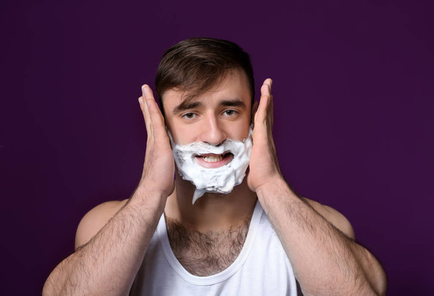 Handsome man with shaving foam on his face against color background - Photo, Image