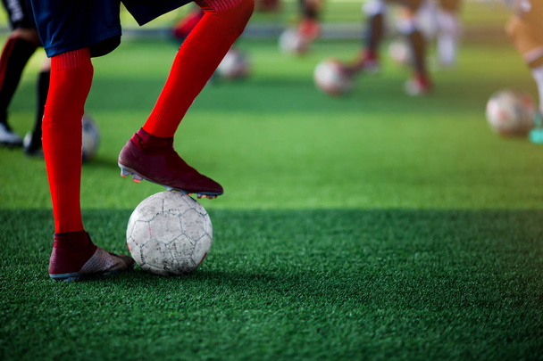 Παίκτης ποδοσφαίρου στέκεται και σχετικά με την ενίσχυση την μπάλα με θολή ποδοσφαιριστή κατάρτισης. - Φωτογραφία, εικόνα