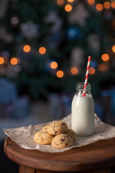 Свежие шоколадные печенье с молоком для Санты на деревянном столе, с темным фоном елки и место для текста
 - Фото, изображение