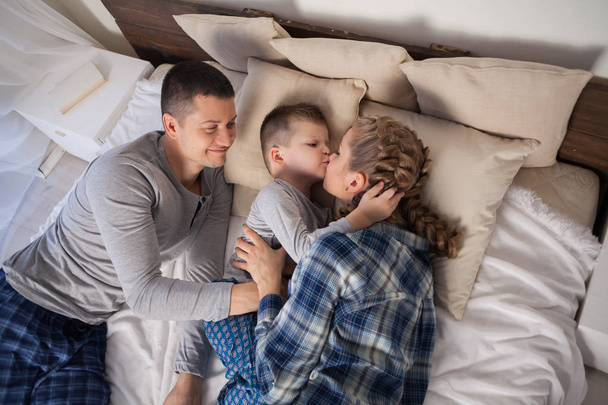 μπαμπάς μαμά και νεαρό γιο του ύπνου στο κρεβάτι στην κρεβατοκάμαρα - Φωτογραφία, εικόνα