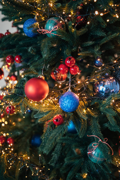 光沢のあるつまらないものとライトの花輪で飾られた美しいクリスマス ツリー   - 写真・画像