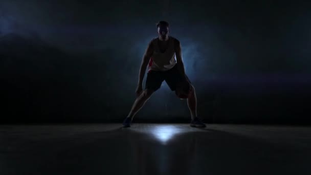 Geschicklichkeit dribbelnder Basketballspieler im Dunkeln auf dem Basketballplatz mit Gegenlicht im Rauch. Streetball in Zeitlupe - Filmmaterial, Video