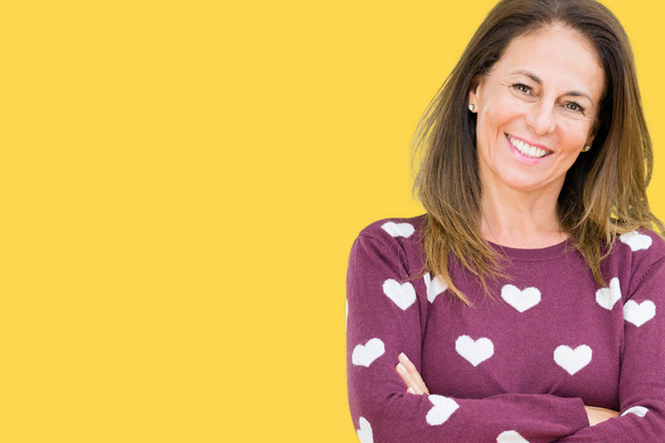 Beautiful middle age woman wearing hearts sweater over isolated background happy face smiling with crossed arms looking at the camera. Positive person. - Foto, afbeelding
