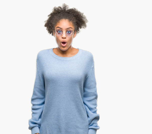 Jeune femme afro-américaine portant des lunettes sur fond isolé effrayée et choquée par l'expression surprise, la peur et le visage excité
. - Photo, image