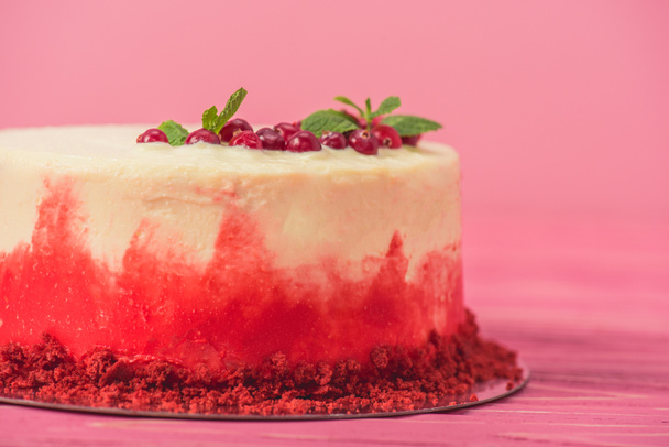 white cake with decorated with red currants and mint leaves isolated on pink - Фото, зображення