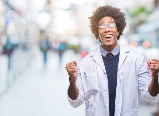 Afro american doctor scientist man over isolated background celebrating mad and crazy for success with arms raised and closed eyes screaming excited. Winner concept - Photo, Image
