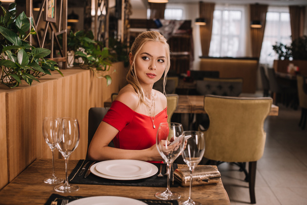 レストランに座っている赤いドレスの魅力的な女性 - 写真・画像
