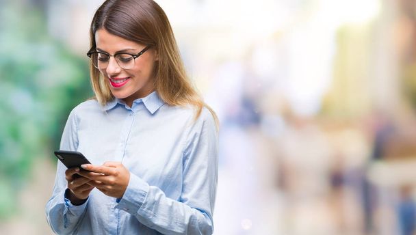 Fiatal gyönyörű üzleti nő textil üzenet használ smartphone elszigetelt háttér mint egy boldog arccal állt, és mosolyogva, magabiztos mosollyal mutatja a fogak - Fotó, kép