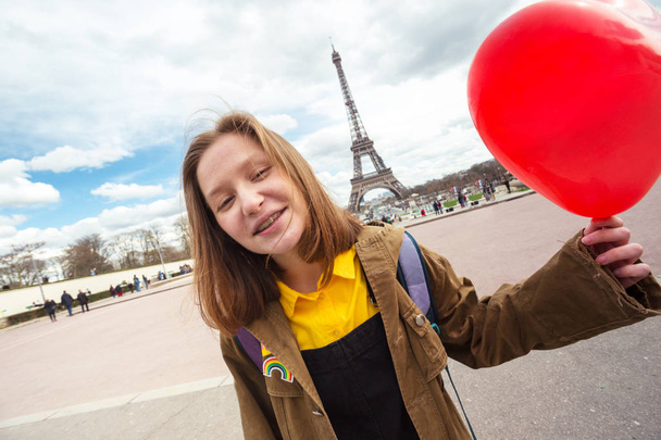 happy and smiling girl student with a balloon in the shape of a heart on the background of the Eiffel Tower in Paris. France - Fotografie, Obrázek
