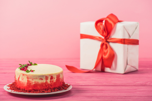 торт, прикрашений смородиною і листя м'яти біля подарункової коробки ізольовані на рожевому
 - Фото, зображення