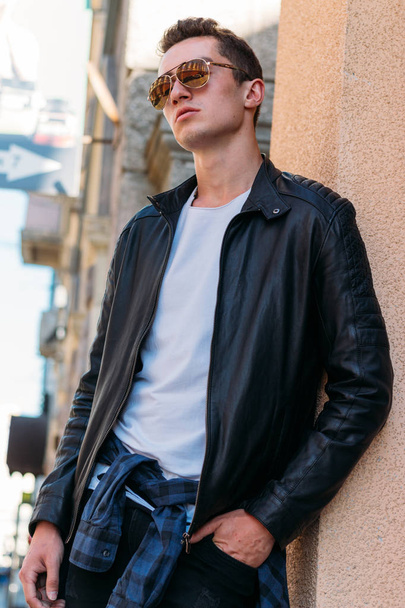 Attractive, sexy guy standing on the street in sunglasses. self-confidence, flatulence and arrogance.model, posing, portrait of a young man - Zdjęcie, obraz