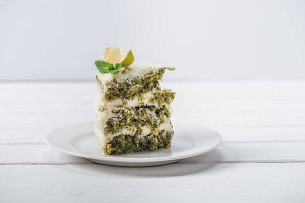 кусок белого торта украшенный листьями мяты и ломтиками линии на блюдце изолированы на белом
  - Фото, изображение