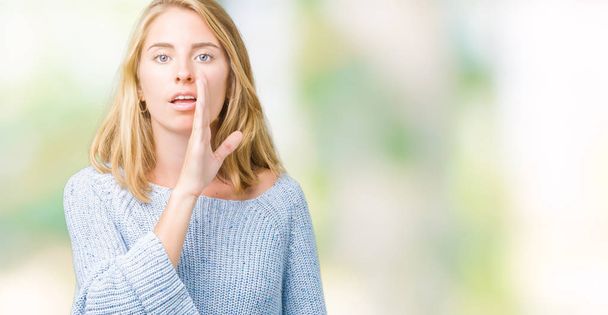 Piękna młoda kobieta sobie niebieski sweter na na białym tle dłoń na ustach mówi sekret plotka, szepcząc złośliwy rozmowa rozmowy - Zdjęcie, obraz