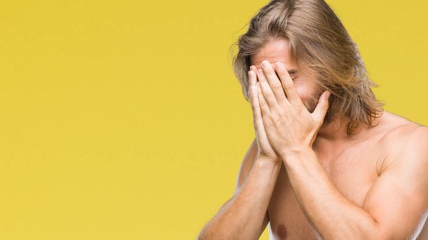 Young handsome shirtless man with long hair showing sexy body over isolated background with sad expression covering face with hands while crying. Depression concept. - Photo, Image