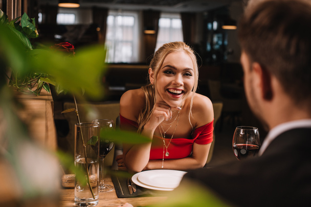 enfoque selectivo de chica alegre mirando al hombre y riendo en el restaurante
  - Foto, Imagen