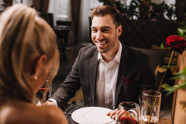 handsome man laughing in restaurant while looking at woman  - Fotografie, Obrázek
