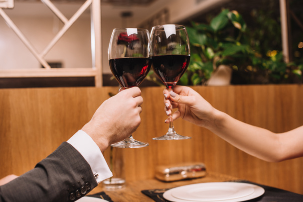 cropped view of couple toasting with glasses of red wine on valentines day - Фото, изображение
