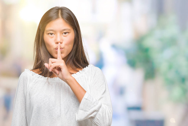 Молода азіатка над ізольованим тлом просить мовчати з пальцем на губах. Тиша і таємна концепція
. - Фото, зображення
