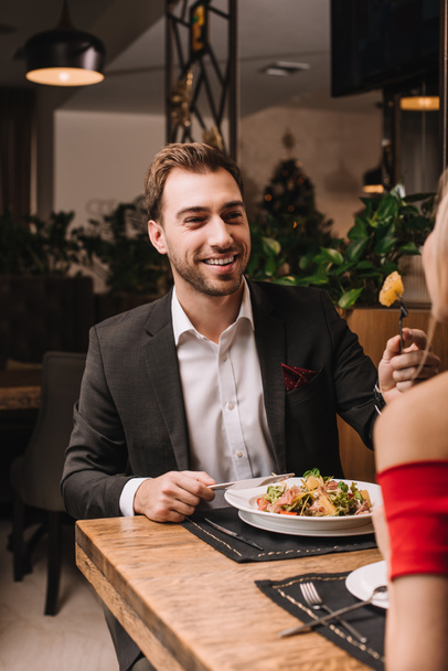 handsome man feeding girlfriend with salad in restaurant - Foto, afbeelding