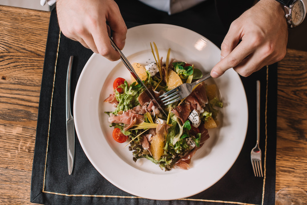 top view of man holding cutlery near tasty salad  - Foto, Bild