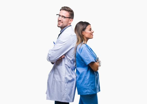 Jeune couple de médecin et chirurgien sur fond isolé heureux visage souriant avec les bras croisés en regardant la caméra. Personne positive
. - Photo, image