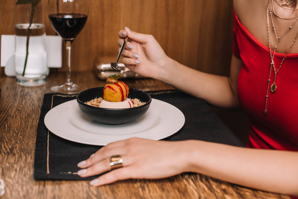 female hand holding spoon near sweet dessert in bowl - Foto, afbeelding