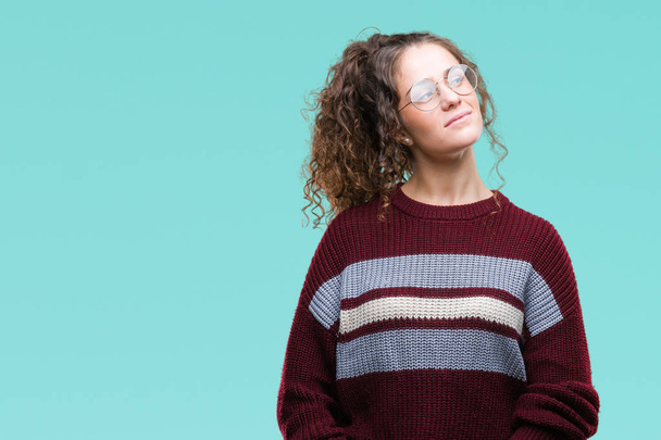 Beautiful brunette curly hair young girl wearing glasses over isolated background smiling looking side and staring away thinking. - Foto, Imagem
