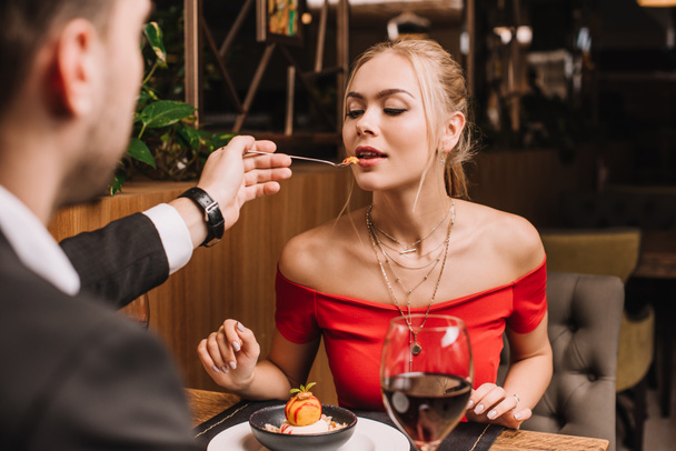 boyfriend feeding woman with sweet dessert in restaurant - Foto, Imagem