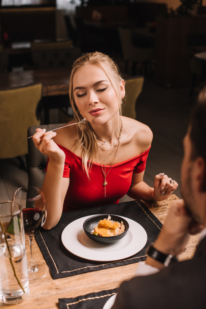 girlfriend eating sweet dessert while sitting near boyfriend in restaurant - Foto, Imagem