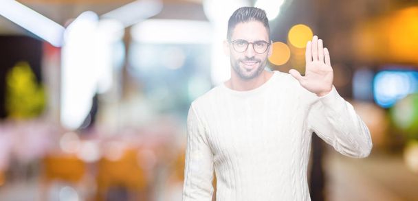junger gutaussehender Mann mit Brille über isoliertem Hintergrund, der auf ein fröhliches Hallo und eine freundliche Willkommensgeste verzichtet - Foto, Bild
