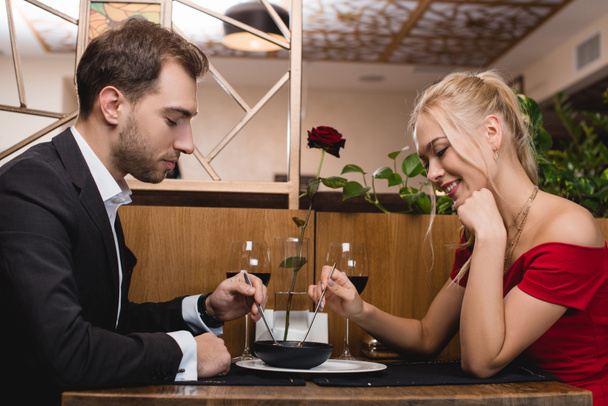 happy couple sharing dessert while sitting in restaurant  - Photo, Image