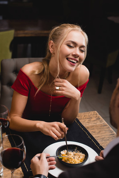 happy woman laughing  near boyfriend while sharing dessert in restaurant - Zdjęcie, obraz