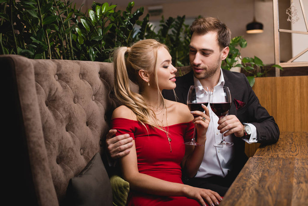 attractive woman toasting with glass of red wine with boyfriend in restaurant  - Photo, Image