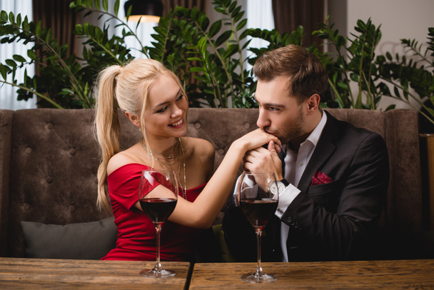 schöner Mann küsst die Hand einer attraktiven Frau im Restaurant bei einem romantischen Date - Foto, Bild