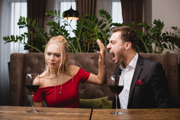 offeso donna gesticolando per smettere di urlare fidanzato nel ristorante
  - Foto, immagini