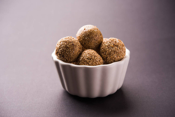 Tilgul Laddu или Til Gul шарики для Makar sankranti, это здоровая пища, приготовленная с использованием кунжута, дробленых арахиса и jaggery. подается в миске. селективный фокус, показывающий детали
. - Фото, изображение