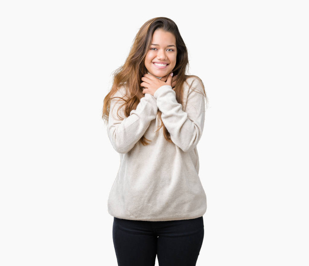 Όμορφη μελαχρινή νεαρή γυναίκα φορώντας ζιβάγκο πουλόβερ πάνω από απομονωμένες φόντο φωνάζοντας και ασφυκτιούν επειδή επώδυνη στραγγαλίσει. Πρόβλημα υγείας. Προκαλέσουν ασφυξία και η έννοια της αυτοκτονίας. - Φωτογραφία, εικόνα