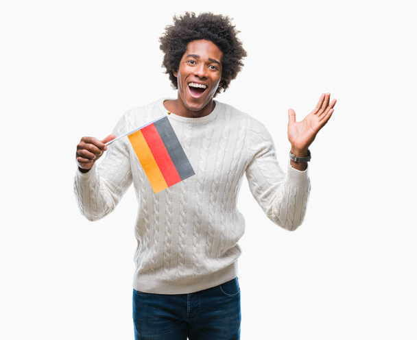 Afro american człowiek flaga Niemiec na białym tle bardzo szczęśliwy i podekscytowany, zwycięzca wyrażenie świętuje zwycięstwo krzyczy z uśmiechem i ręce - Zdjęcie, obraz