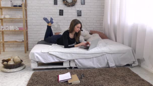 Молодая женщина работает с ноутбуком на кровати
 - Кадры, видео