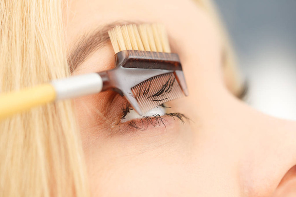Close up of woman doing her make up, preparing lashes using brush tool brushing eyelashes. - Foto, Imagem