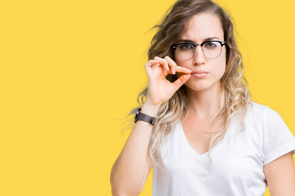 Beautiful young blonde woman wearing glasses over isolated background mouth and lips shut as zip with fingers. Secret and silent, taboo talking - Photo, Image
