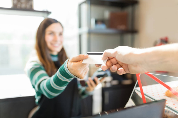 Imagen recortada del cliente dando tarjeta de crédito a cajero en panadería
 - Foto, imagen