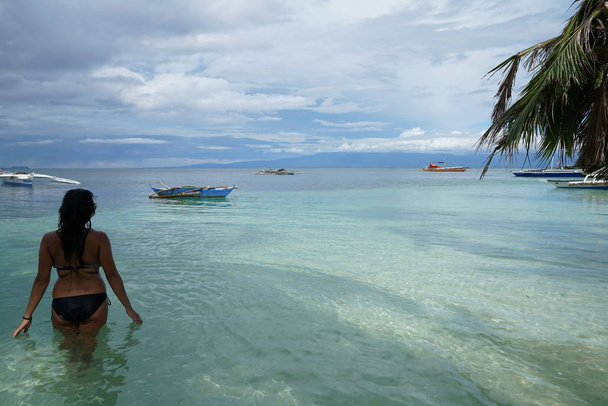 visão traseira da mulher em pé na água do mar
  - Foto, Imagem