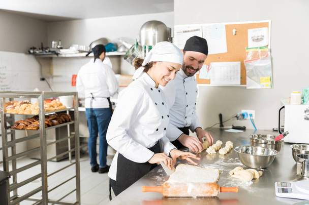 Happy bakers making dough for bread pastries in restaurant kitchen - Foto, Imagen